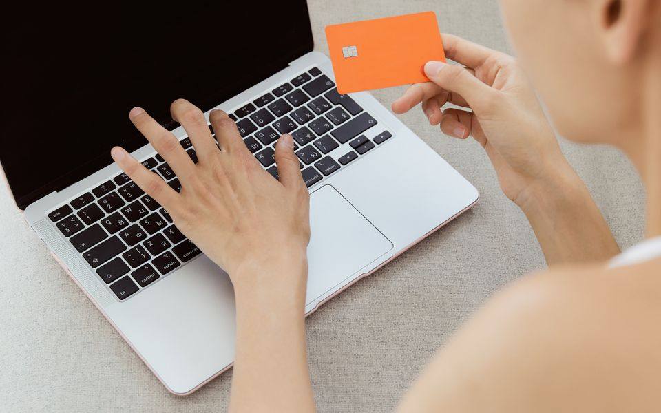Wanita menggunakan kartu bank dan laptop untuk transaksi daring