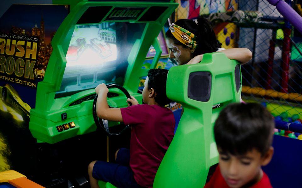 Deretan mesin permainan berwarna-warni di lantai arcade